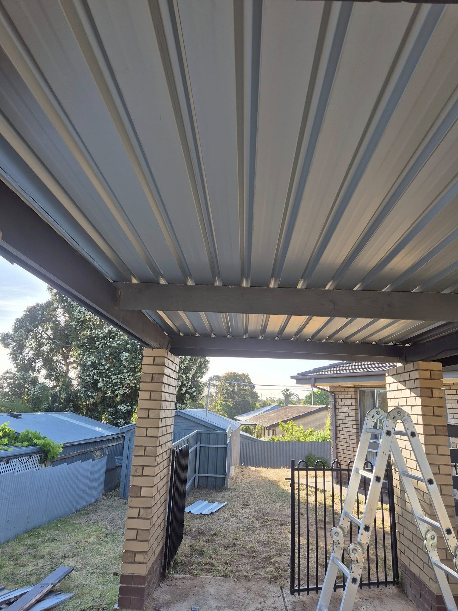 New carport roof sheeting fitted over brick piers