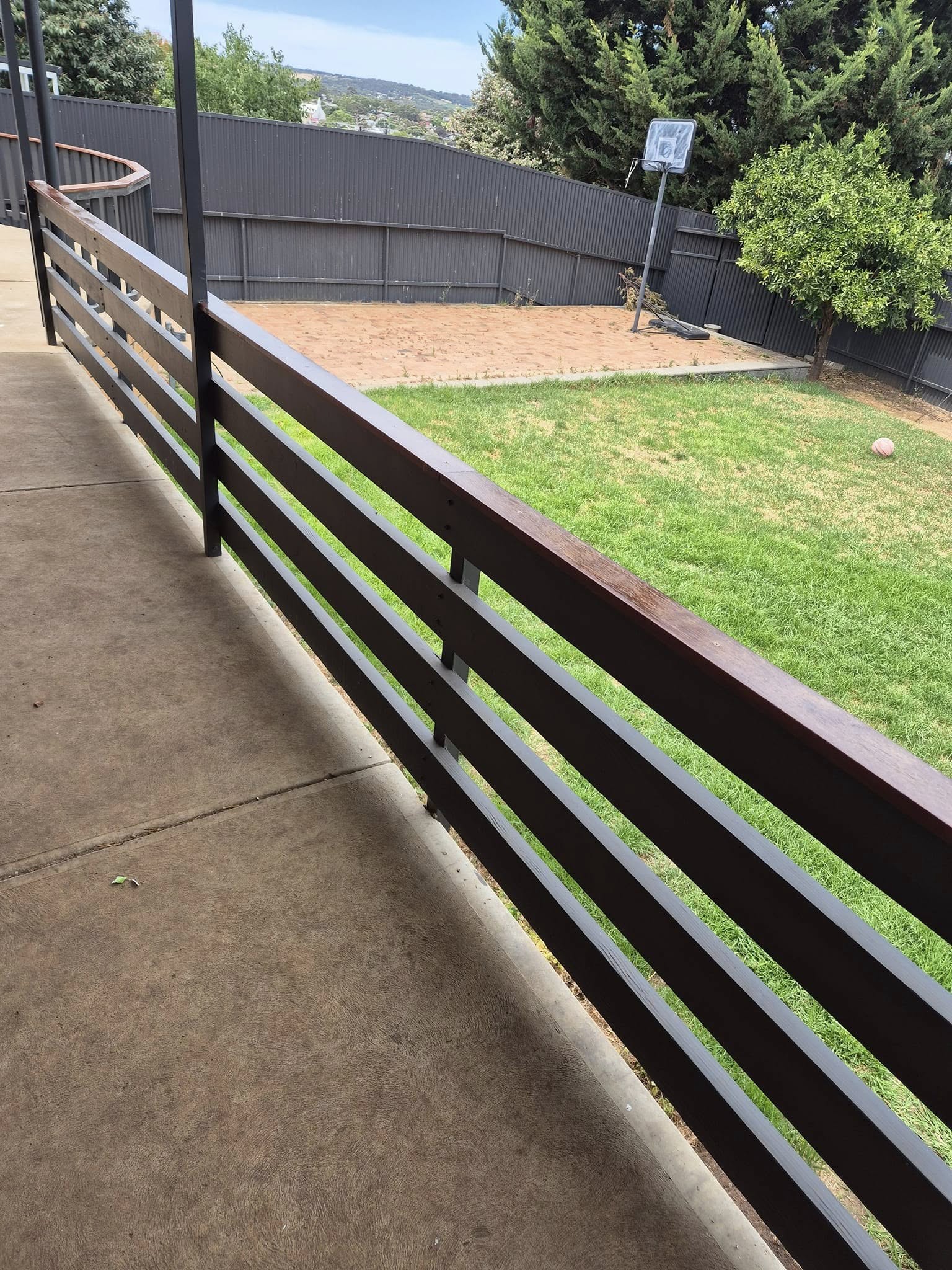 Stained timber balustrade running along a concrete path