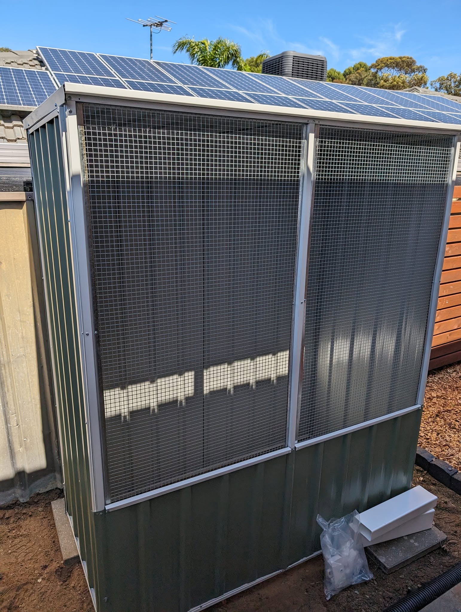 New green garden shed with mesh doors built beside a fence