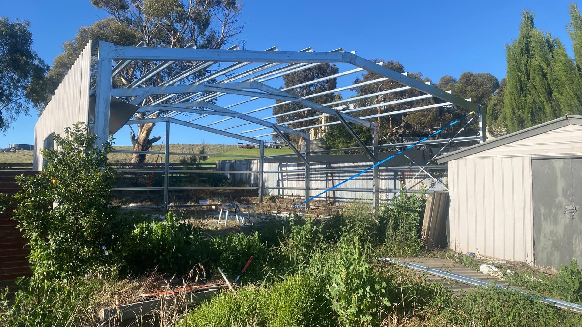 Steel frame of a large shed standing in a paddock